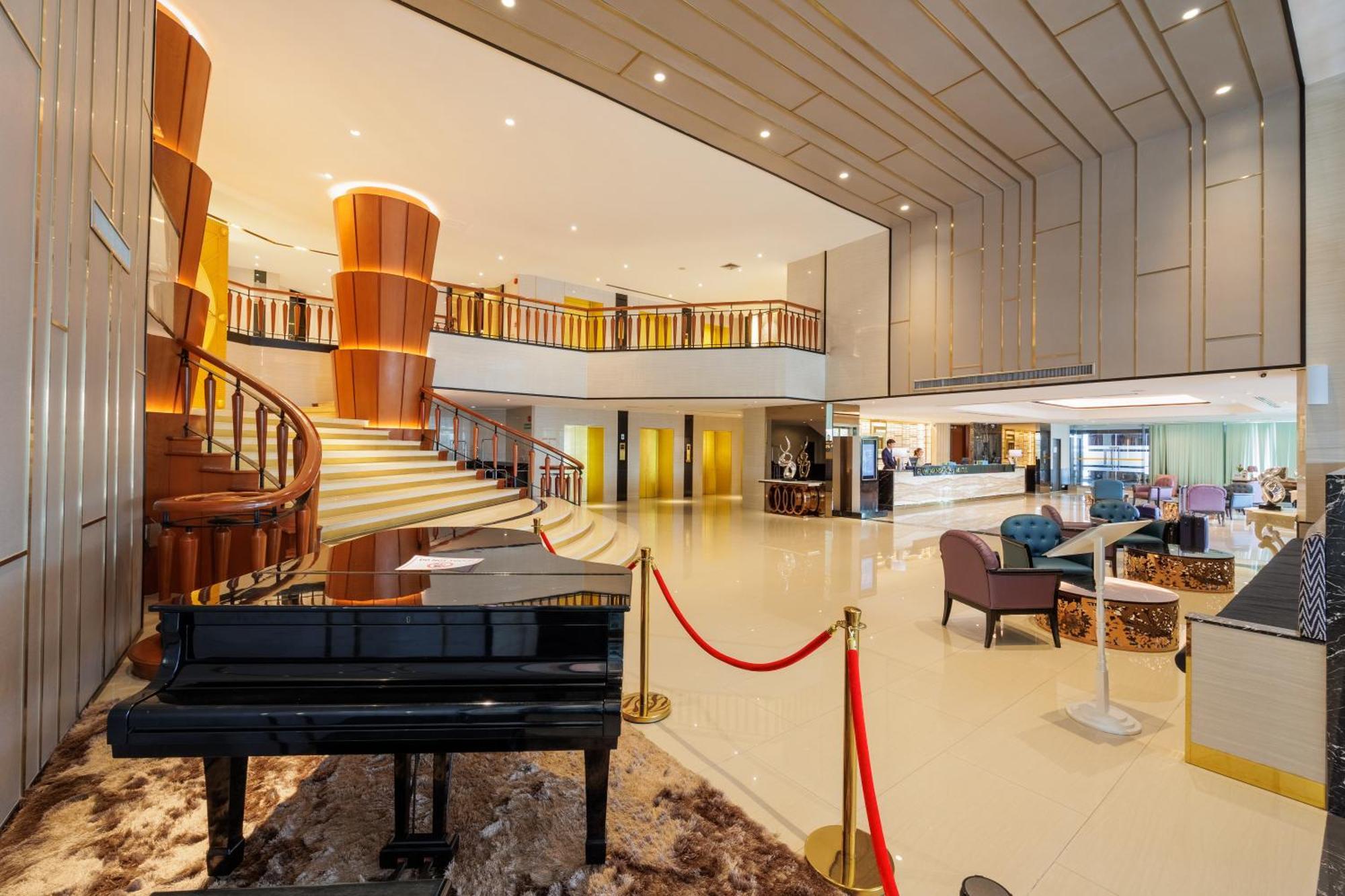 Siam Mandarina Hotel - Free Bkk Airport Shuttle Samut Prakan Exterior photo The photo shows a modern hotel lobby with an elegant design. In the foreground, there is a grand piano positioned on a rug, complemented by a red rope barrier. The lobby features a spacious layout with a winding staircase leading to an upper level. T